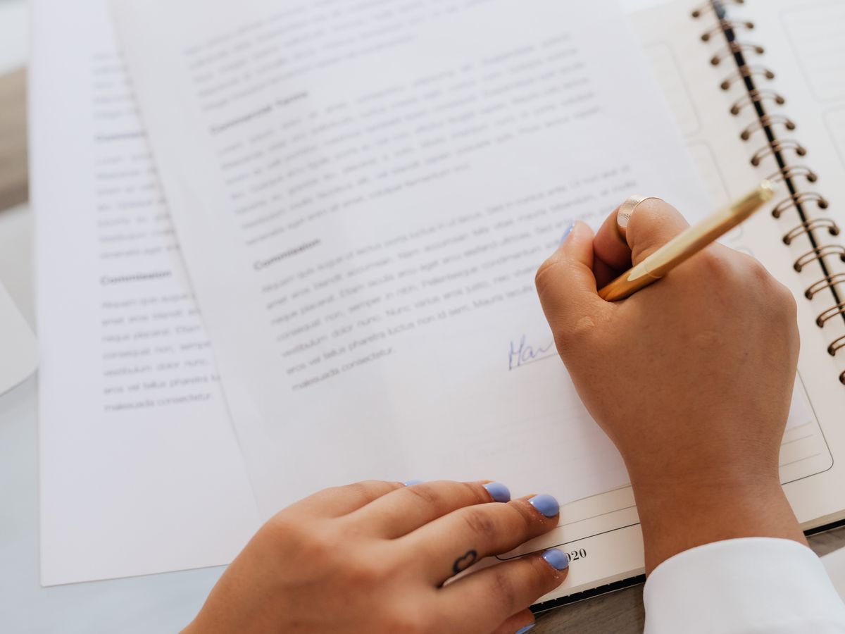 Signing a business document at a desk with a gold pen